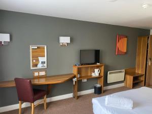 a hotel room with a desk and a tv at Days Inn Corley NEC - M6 in Coventry