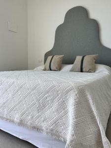 a bedroom with a white bed with a large headboard at NOTO country farm house in Noto
