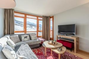 Il comprend un salon doté d'un canapé et d'une télévision à écran plat. dans l'établissement Les Arcs 1800 : Appartement ski in/out avec spa, à Bourg-Saint-Maurice