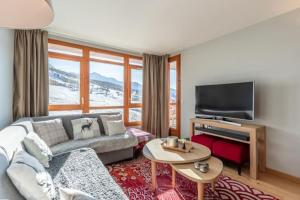 a living room with a couch and a flat screen tv at Les Arcs 1800 : Appartement ski in/out avec spa in Bourg-Saint-Maurice