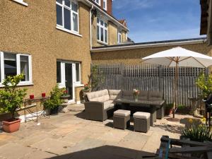 une terrasse avec un canapé, une table et un parasol dans l'établissement Residential 3 bed house Harnham, à Salisbury