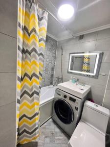 a bathroom with a washing machine and a shower curtain at 2-х комнатная квартира в центре in Almaty +8 photos