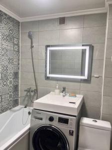 a bathroom with a washing machine under a sink at 2-х комнатная квартира в центре in Almaty