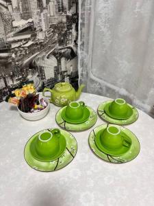 a table with four green cups and plates on it at 2-х комнатная квартира в центре in Almaty