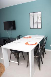 einen weißen Esstisch mit schwarzen Stühlen und einem TV in der Unterkunft Studio tout équipé centre-Ville proche de la gare in Cluses