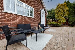 two chairs and a table in front of a brick house at Silver Stag Properties, Luxurious 3 BR Bungalow in Worthington