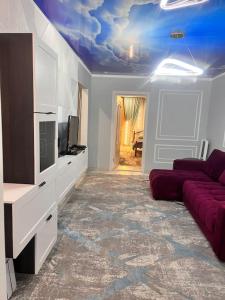 ein Wohnzimmer mit Sofa und Fernseher in der Unterkunft 2-х комнатная квартира на Арбате in Almaty