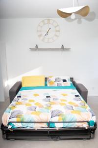 Bett in einem Zimmer mit einer Uhr an der Wand in der Unterkunft Studio tout équipé centre-Ville proche de la gare in Cluses