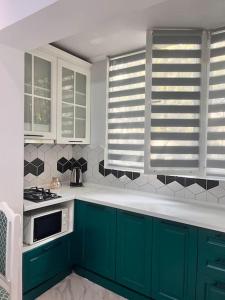 eine Küche mit grünen Schränken und einer weißen Arbeitsplatte in der Unterkunft 2-х комнатная квартира на Арбате in Almaty