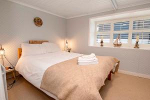 Un dormitorio con una gran cama blanca y una ventana en Traditional Cottage with Private Hot Tub in the Heart of Donegal en Letterkenny