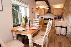 una cucina con tavolo in legno con sedie e una sala da pranzo di Traditional Cottage with Private Hot Tub in the Heart of Donegal a Letterkenny