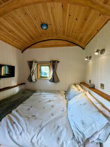 Cama grande en habitación con techo de madera en Romantic Escape with Hot Tub & Countryside Views, en Leominster