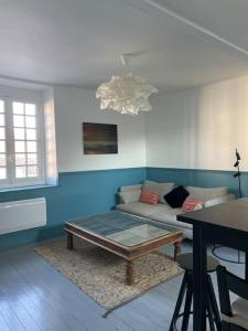 een woonkamer met een bank en een tafel bij En plein coeur du Crotoy, un pied à terre en Baie in Le Crotoy