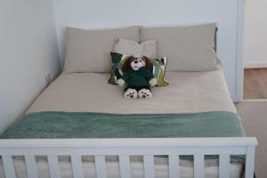 a teddy bear sitting on top of a bed at Cosy Flat in Cambridge in Milton