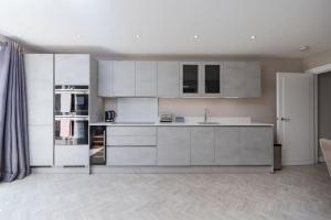 a kitchen with white cabinets and appliances in a room at West Kensington by Capital in London