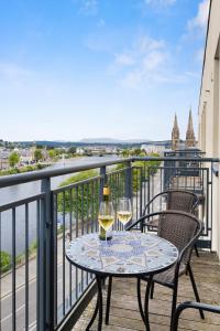 a table with two glasses of wine on a balcony at By the Bridge by Toppo in Inverness