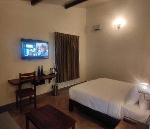 a hotel room with a bed and a television at Mango Hill Kodai in Kodaikānāl