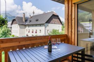 a table with wine glasses on a balcony with a building at Apartments Am Dorfplatzl in Hohentauern