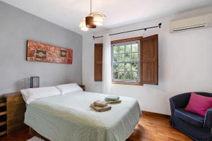 a bedroom with a bed and a chair and a window at Tegueste Entre Viñedos in Tegueste