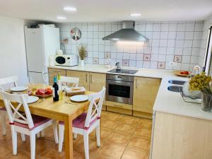 uma cozinha com uma mesa e cadeiras de madeira e uma cozinha com electrodomésticos brancos em Casa rústica con encanto en La Puebla de Arenoso em Puebla de Arenoso