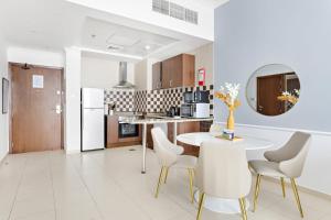 eine weiße Küche mit einem Tisch, Stühlen und einer Theke in der Unterkunft Silkhaus Luxurious Pool & Gym 1BDR Art Residence in Dubai