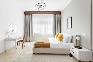 Habitación blanca con cama y escritorio en Silkhaus Furnished Pool & Gym 1BDR Art Residence en Dubái