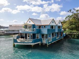 a blue house on a boat in the water at Bay of Islands Apartment On The Water- The Bridge in Opua