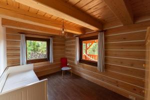 Cabaña de madera con cama y silla roja en Moderní šumavská roubenka s výhledem na Boubín en Vimperk