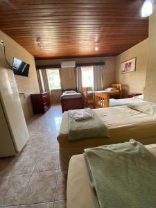 Habitación de hotel con 2 camas y mesa en Pousada Do Pancho en Maricá