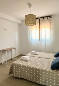 Apartamentos El Camino Resorts في كوبرسيز: غرفة نوم بيضاء مع سرير وطاولة