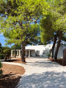 a white house with trees in front of it at Villaria Luxury apulian villa with pool in Campomarino