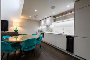 a kitchen with a table and some blue chairs at Chancery Lane by Capital in London