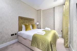 a bedroom with a large bed with yellow pillows at Chancery Lane by Capital in London