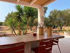 a table and chairs on a patio with palm trees at Villaria Luxury apulian villa with pool in Campomarino