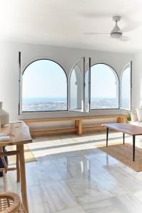 a living room with three windows and a table at Casa Sierra - Mijas Pueblo in Mijas