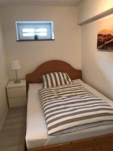 a bedroom with a bed with a striped bedspread and a window at Wohnung mit eigenem Zugang in Hochdorf