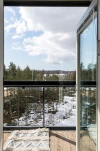 une grande fenêtre avec vue sur une forêt enneigée dans l'établissement Valoisa pikkukaksio Golf-kentän ja järven vieressä, à Kirkkonummi
