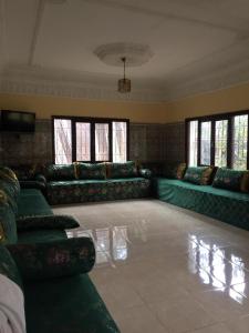 - un grand salon avec des canapés verts et des fenêtres dans l'établissement Villa SLS privé avec piscine privée, à Ourika