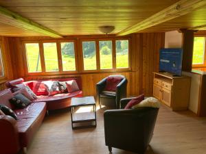 a living room with a couch and chairs and a tv at Weissmies Lodge in Saas-Grund