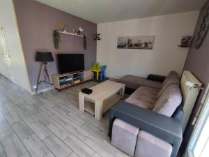 ein Wohnzimmer mit einem Sofa und einem Tisch in der Unterkunft Maison chaleureuse, 35 minutes du zoo in La Chapelle-Montmartin