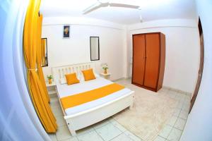 a bedroom with a large bed with orange pillows at Lux Suites Ratna Furnished Apartments in Mombasa