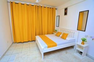 a bedroom with a bed with an orange curtain at Lux Suites Ratna Furnished Apartments in Mombasa