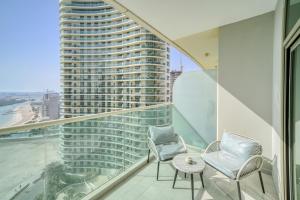 uma varanda com duas cadeiras e uma mesa e um edifício alto em Beach Towers A, Reem Island Abu Dhabi - Mint Stay em Abu Dhabi