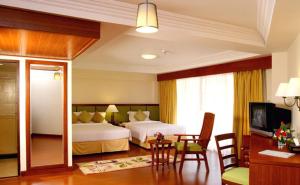 a hotel room with two beds and a table and chairs at Kalim Resort in Patong Beach
