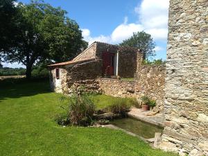 um velho edifício de pedra com uma porta vermelha num quintal em La Petite Maison dans la Prairie em Scillé