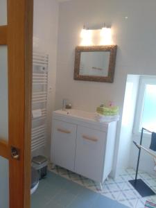 uma casa de banho com um lavatório branco e um espelho. em La Petite Maison dans la Prairie em Scillé