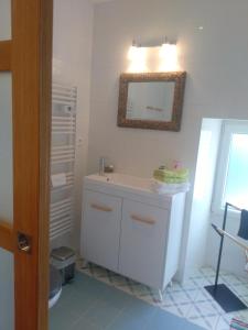 a bathroom with a white sink and a mirror at La Petite Maison dans la Prairie in Scillé