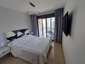ein Schlafzimmer mit einem großen Bett und einem Balkon in der Unterkunft Gemelos24 Benidorm La Cala beach 200m in Benidorm