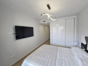 een slaapkamer met een bed en een tv aan de muur bij Gemelos24 Benidorm La Cala beach 200m in Benidorm