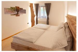 - un lit blanc dans une chambre avec fenêtre dans l'établissement appartamento Bait del Gioti, à Tiarno di Sotto